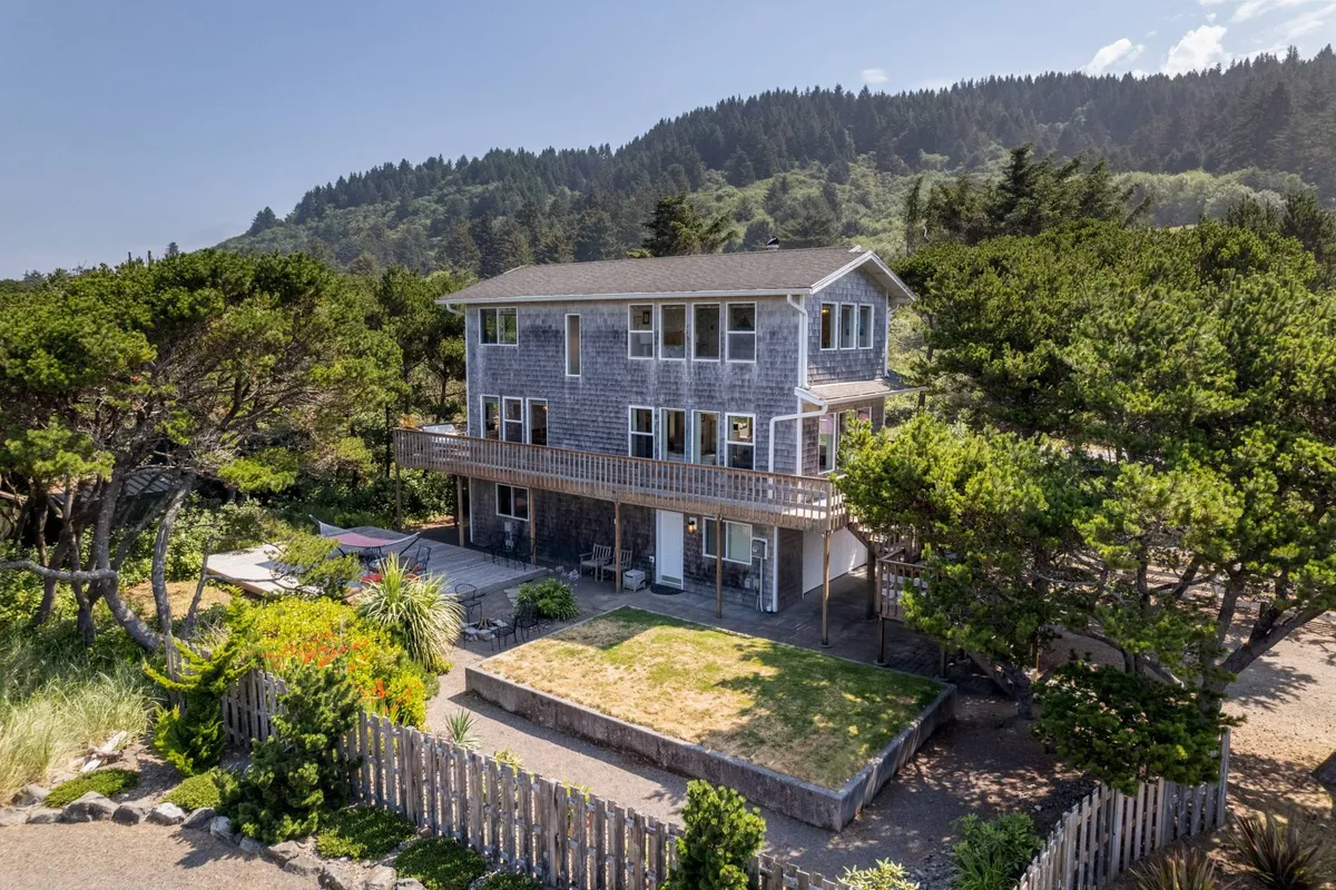 An exterior shot of the house with a spacious deck surrounded by greenery, perfect for outdoor dining, barbecues, and enjoying the fresh air. The deck includes seating areas ideal for gatherings.