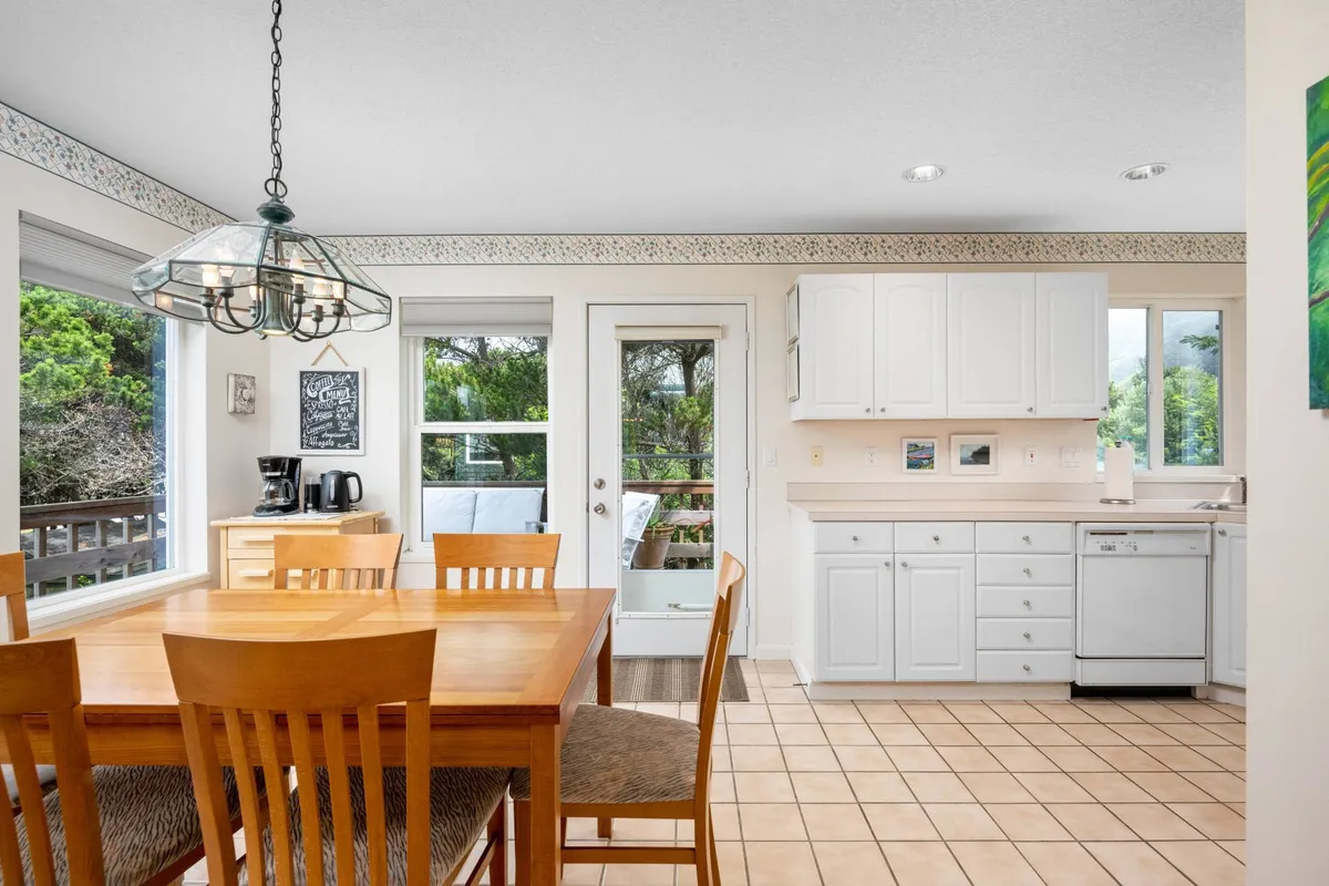 A welcoming dining area with a central dining table, kitchen cabinetry, large windows, and a door leading to the patio. The space is designed for family meals, gatherings, and enjoying the view, with a seamless connection to the rest of the living space.